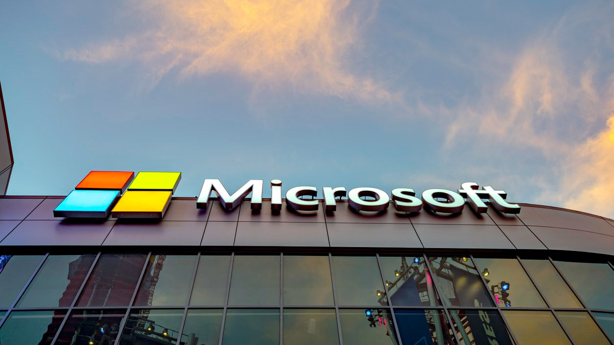 Microsoft logo in front of a building at dusk.