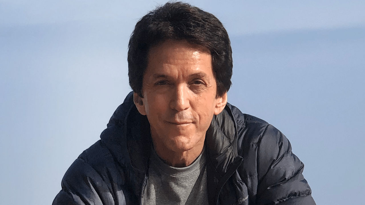 A man in a blue jacket sitting on a rock.