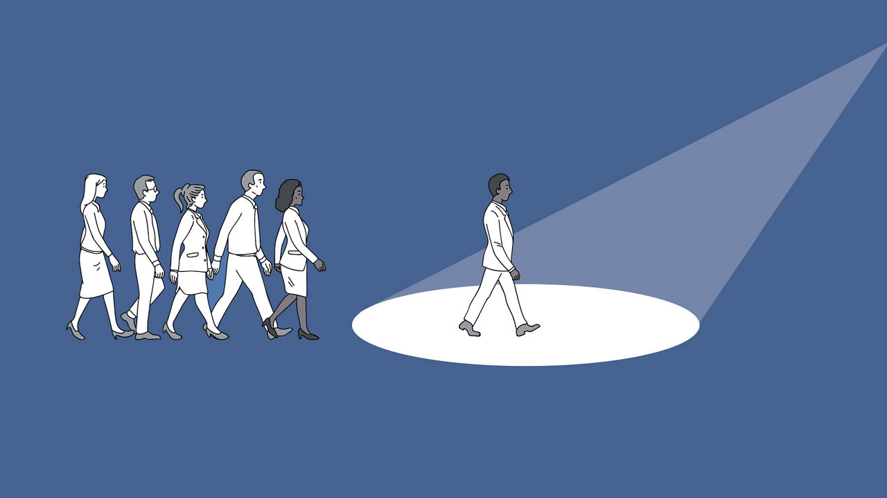 A group of people walking in front of a spotlight.