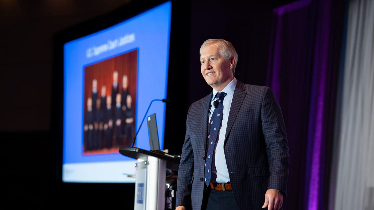 A man in a suit standing at a podium.