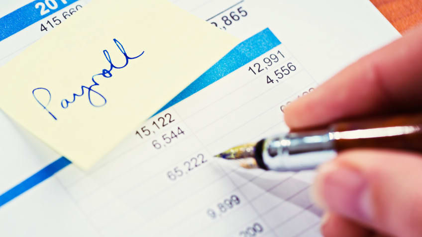 A person writing on a sheet of paper with a pen.