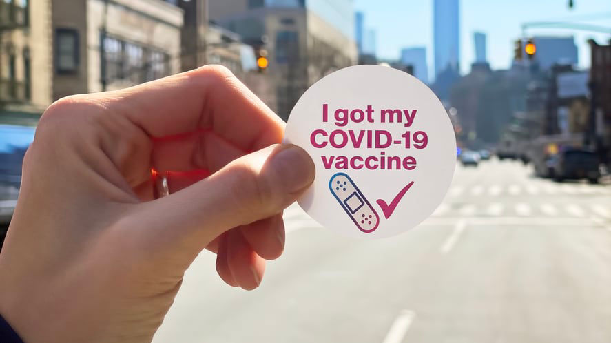 A person holding up a sticker that says i'm not my covid-10.