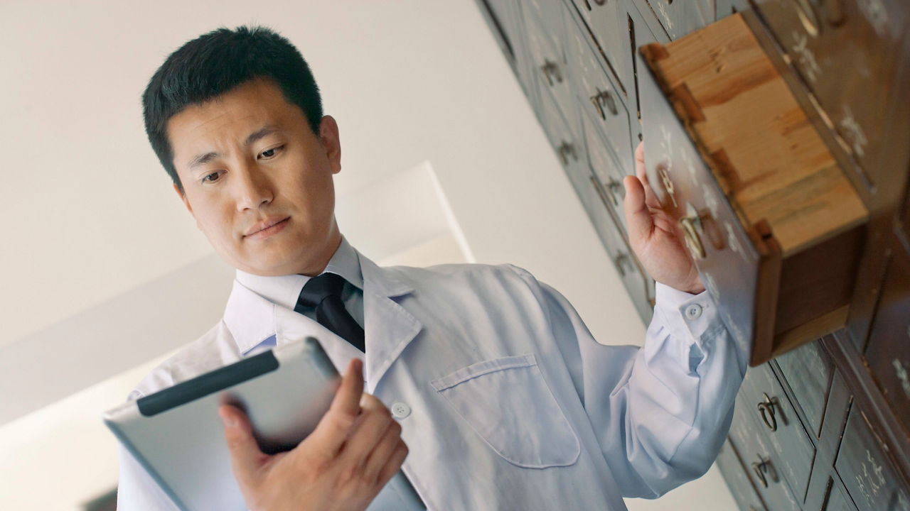 A man in a lab coat holding a tablet.
