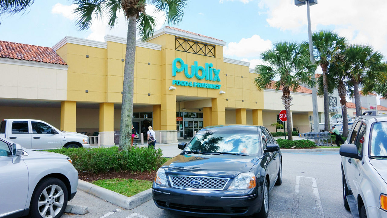 A parking lot with cars parked in front of a shopping center.