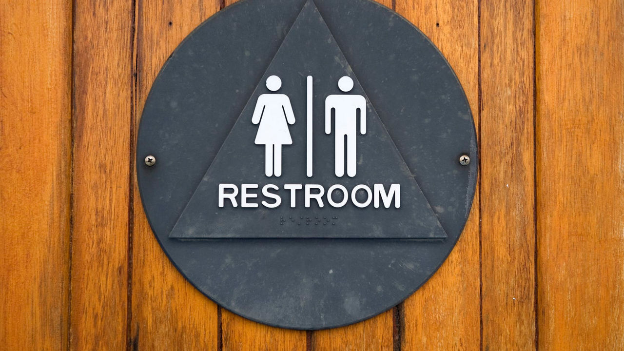 A bathroom sign on a wooden door.