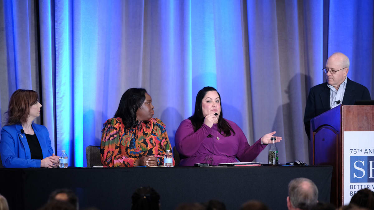 A group of people sitting at a table in front of a podium.