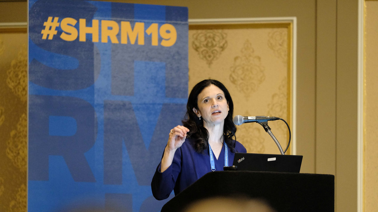 A woman giving a speech at a conference.