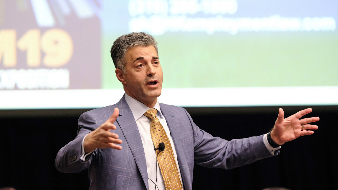 A man in a suit speaking at a conference.