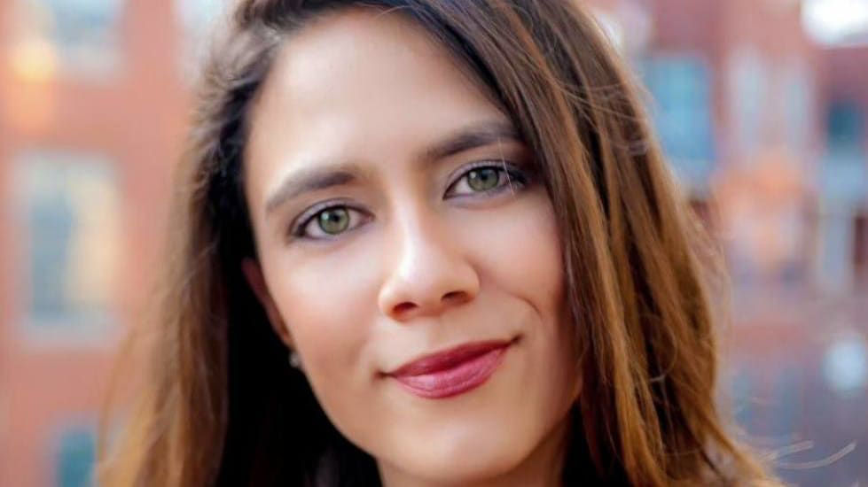 A woman in a black top is posing for a photo.