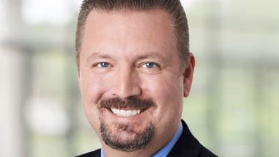 A man in a suit and tie smiles for the camera.