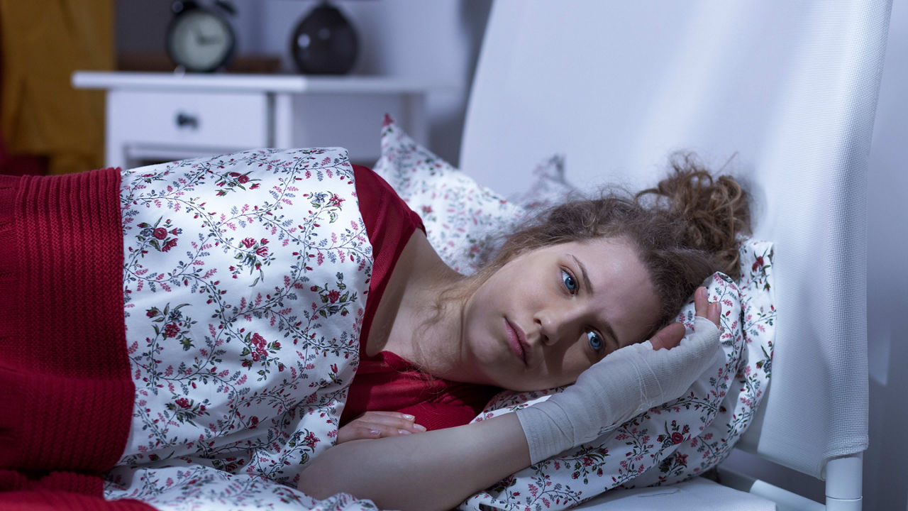 A woman laying in bed with a cast on her arm.