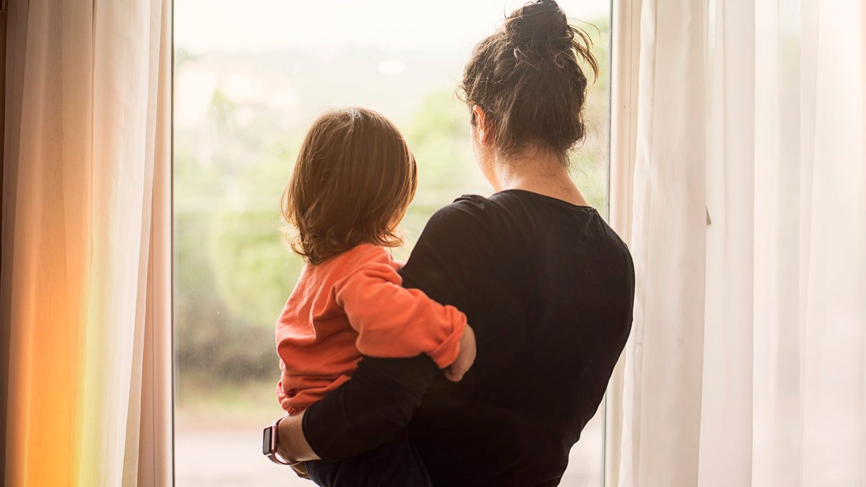 A woman and child looking out a window.