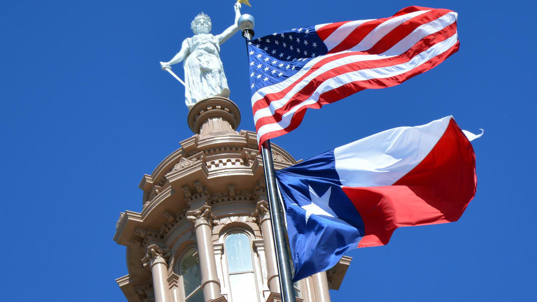 Texas and american flags on top of a building.