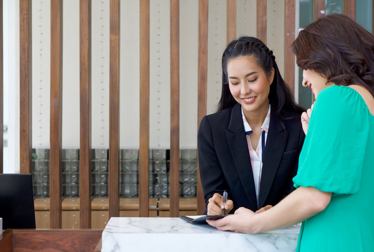 The hotel manager in black suit pointed out the room details in the leather folder with a ballpoint pen. Explain the differences of each room type to young caucasian hotel guest.