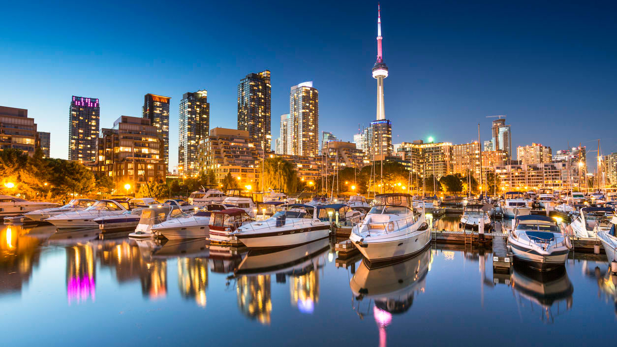 Toronto skyline at dusk with boats docked in the harbor.