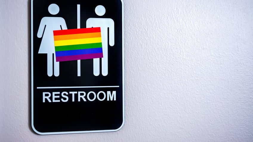 male and female restroom sign with pride flag over it