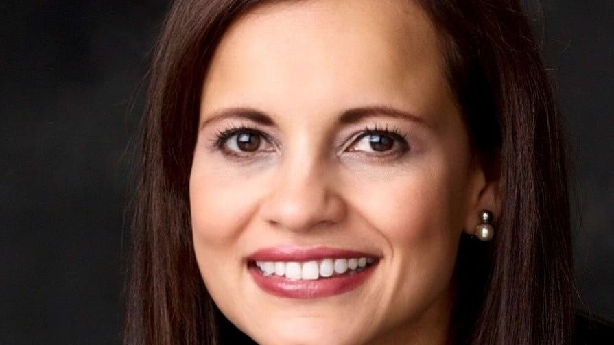 A woman with long brown hair smiling for the camera.