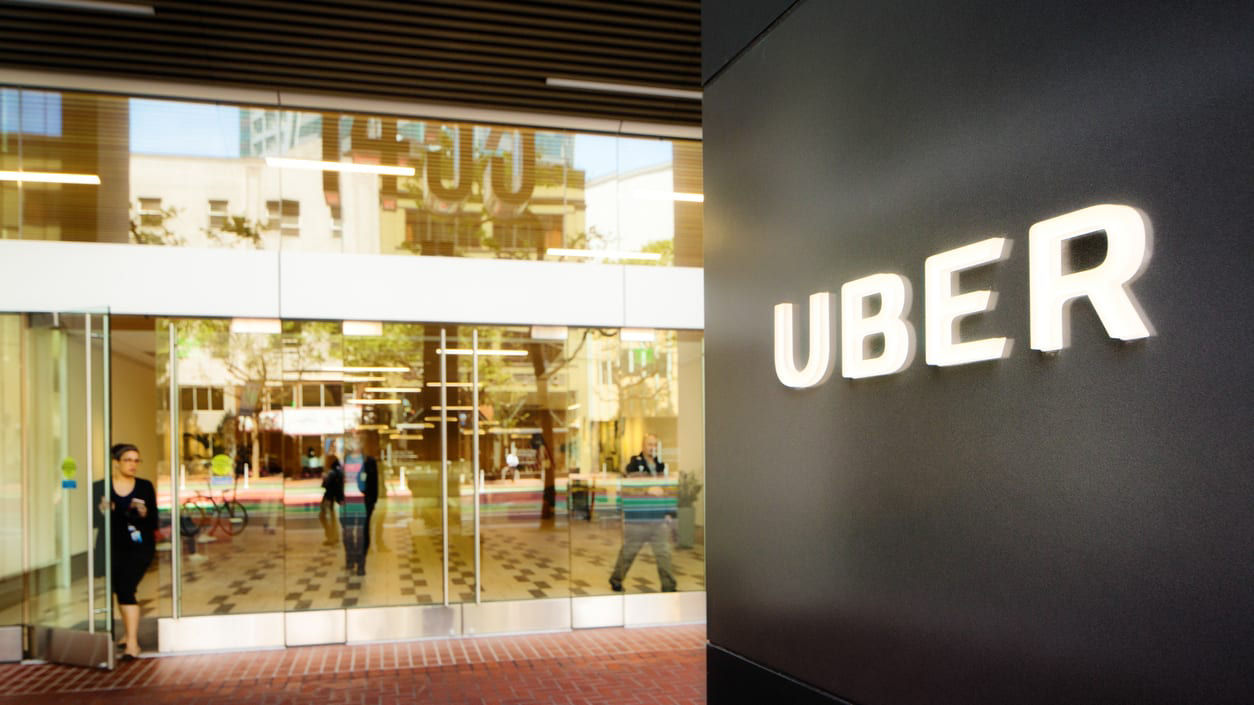 A sign for uber in front of a building.