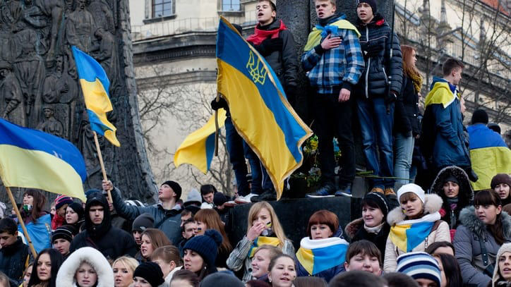 A group of people holding flags in front of a monument.