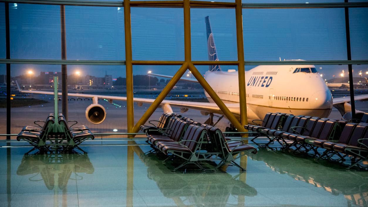 An empty airport waiting room with a plane in the background.