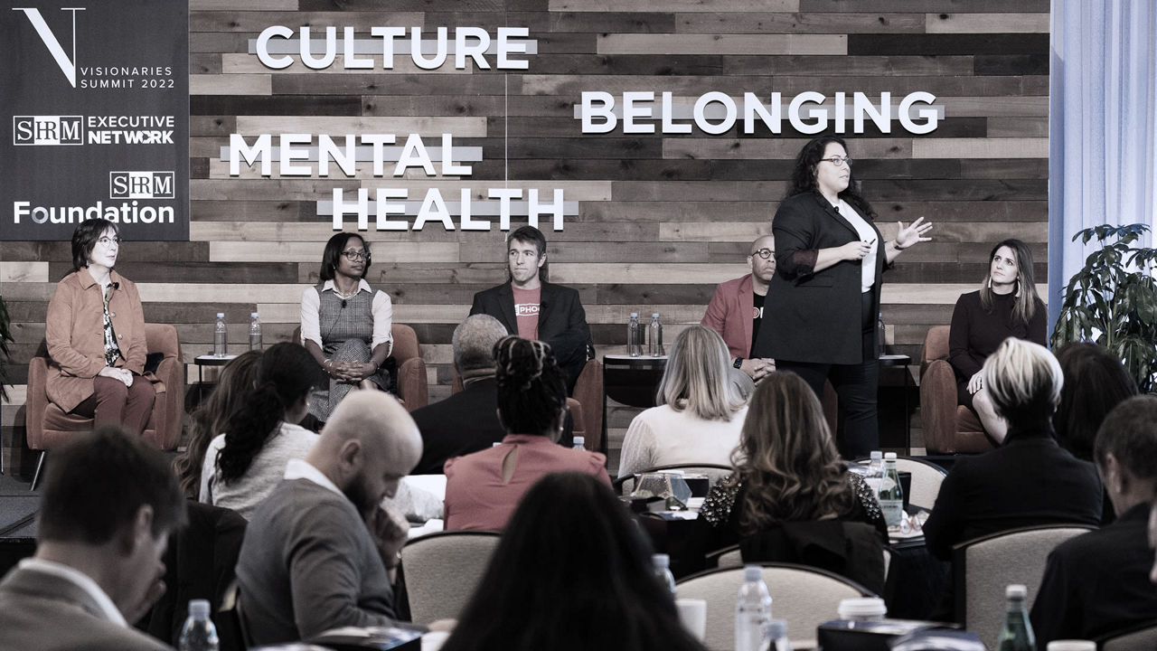 A group of people sitting at a table with the words culture belonging mental health.