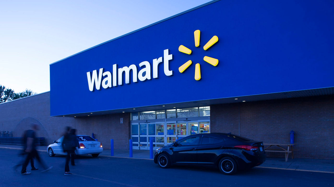 A person walks past a walmart store at dusk.