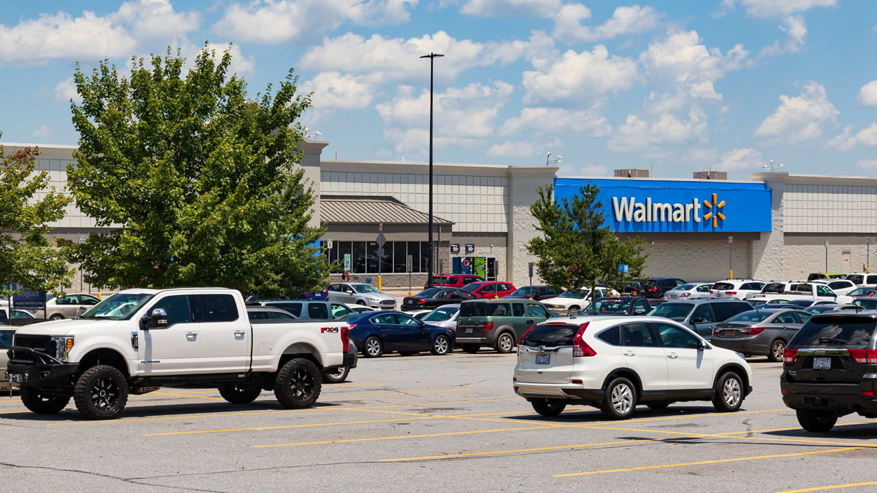 A lot of cars parked in front of a walmart store.