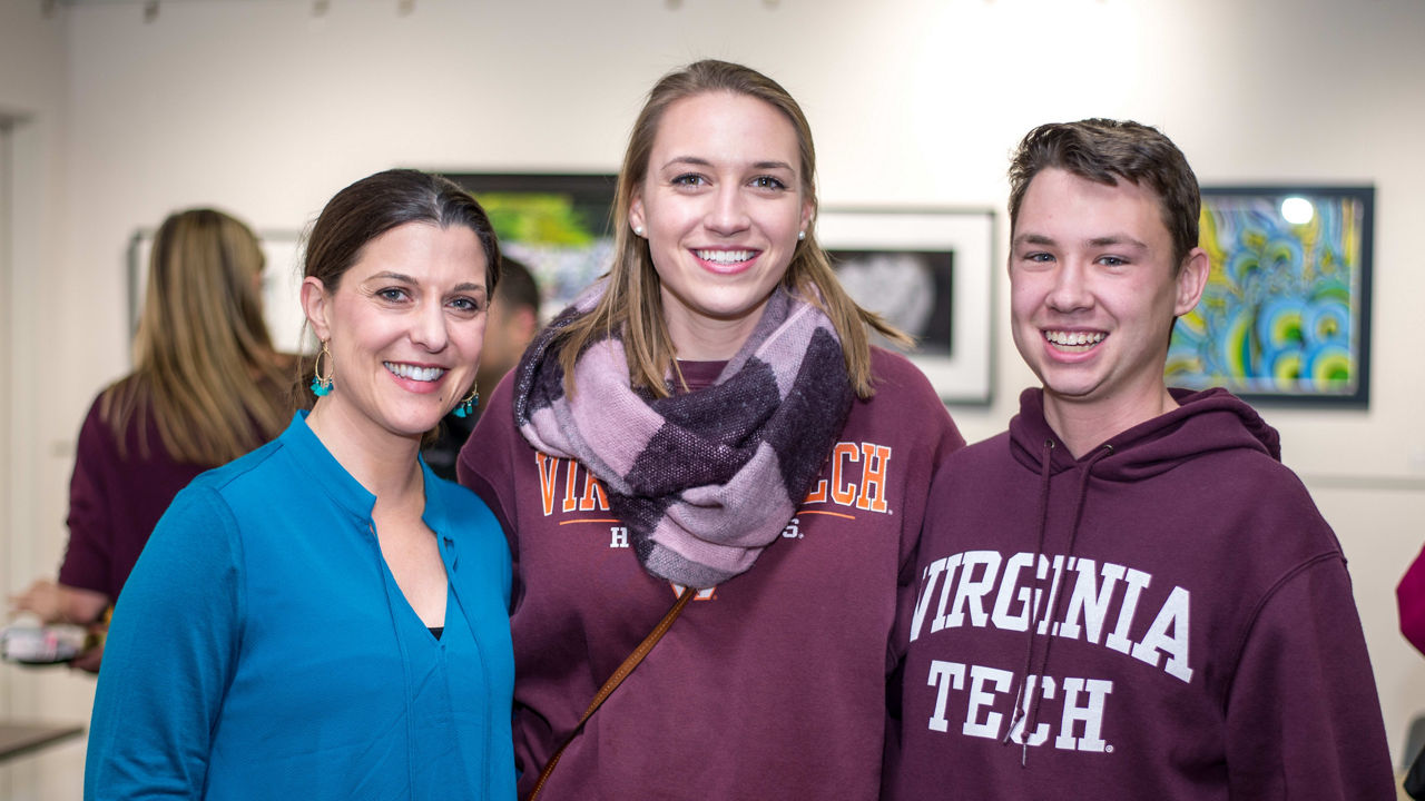 Three people posing for a photo in an art gallery.