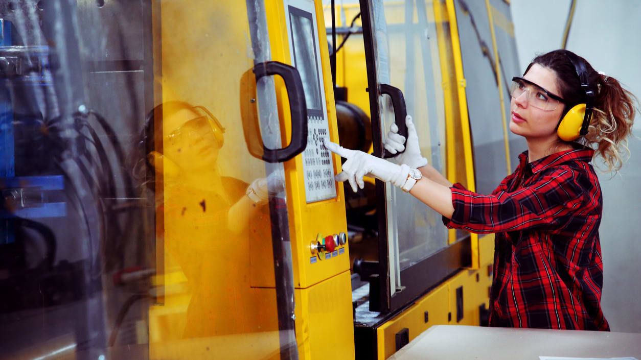 A woman is working on a machine in a factory.