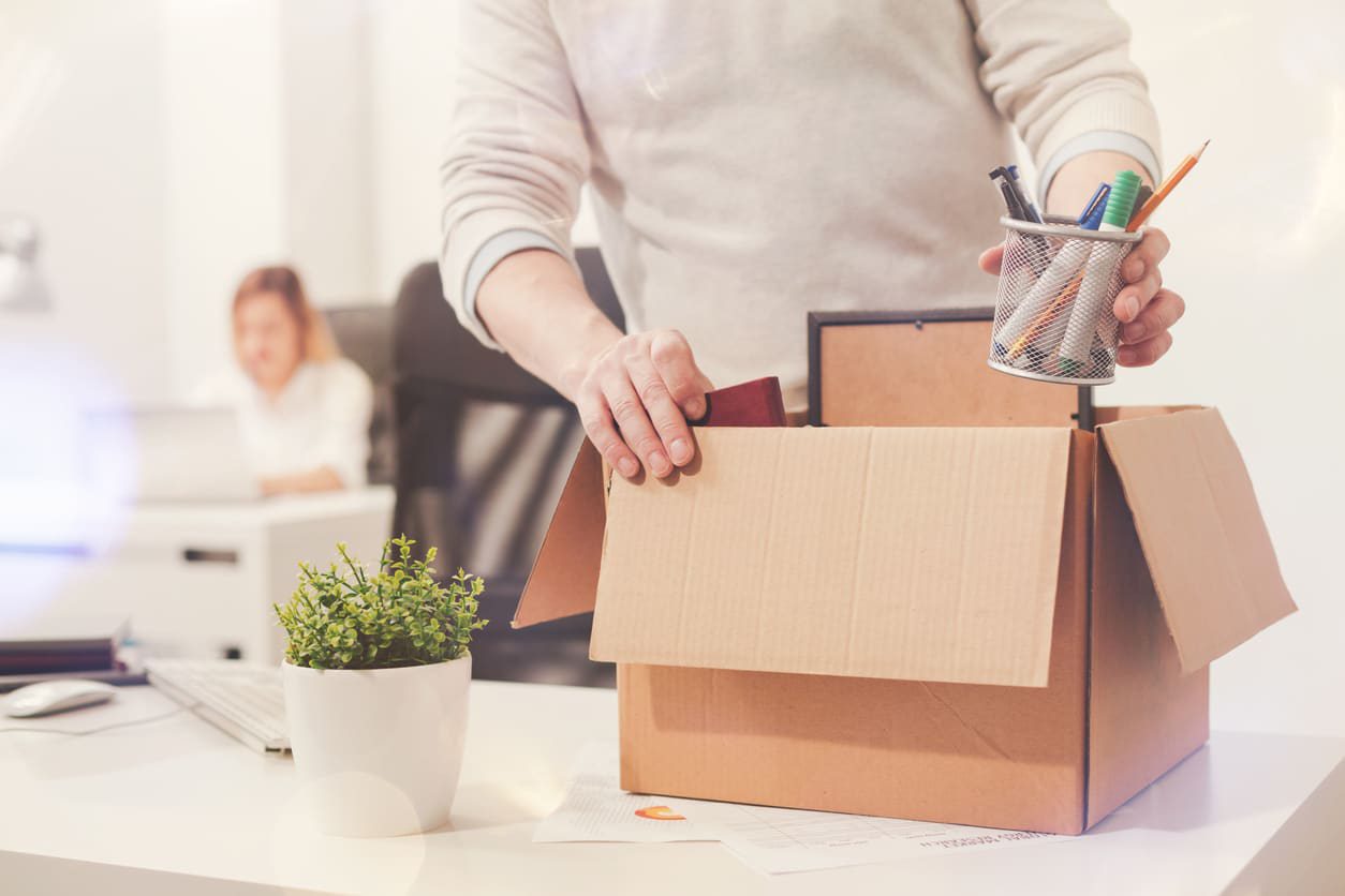 Someone putting personal items from a desk in a box.