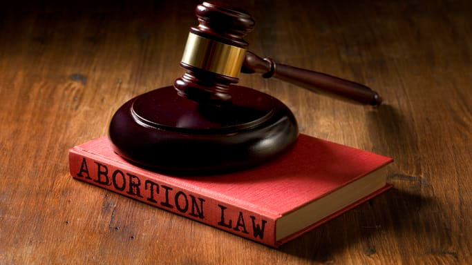A gavel sits on top of a book with the word abortion law.