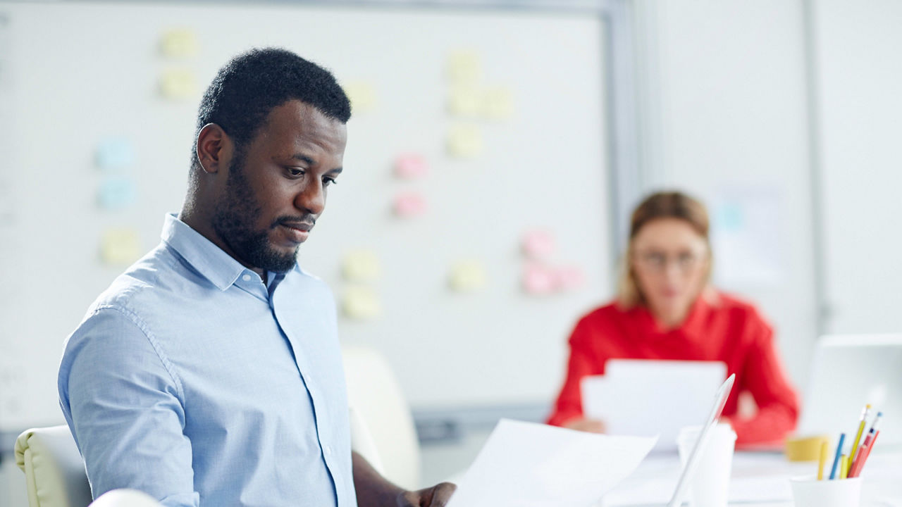 A man and woman are sitting at a desk in an office.