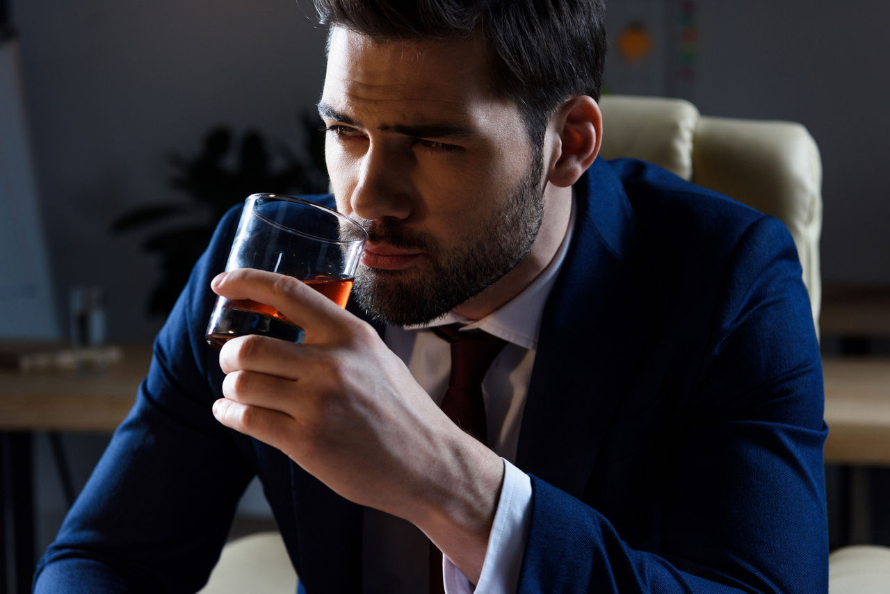 portrait of businessman drinking whiskey and looking away