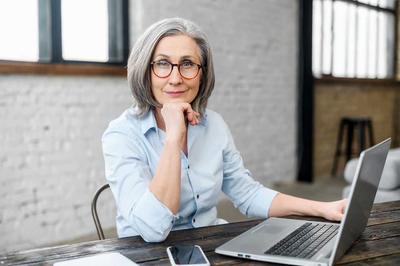 An older worker sits at her computer