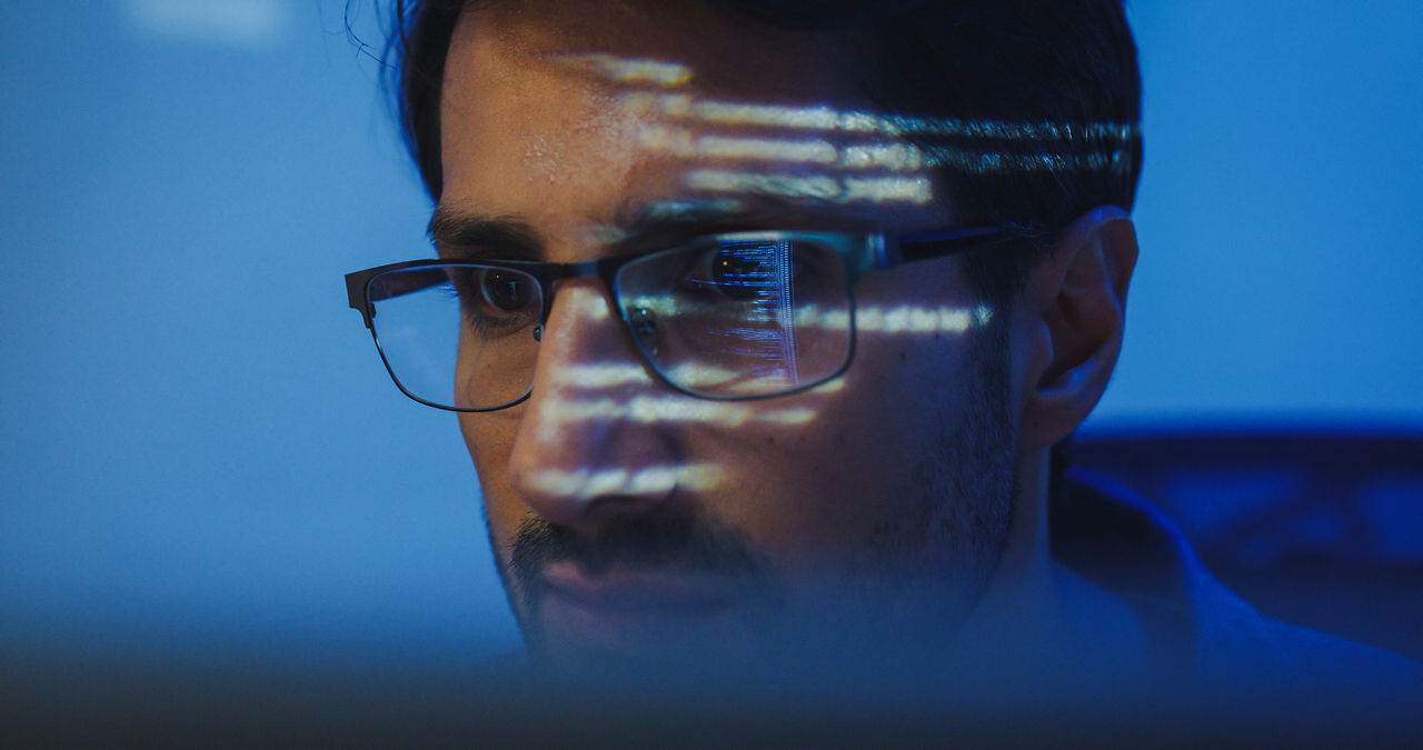 Closeup of male worker wearing glasses with the reflection of a screen