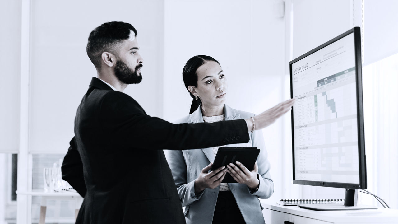 Two business leaders looking at a dashboard 