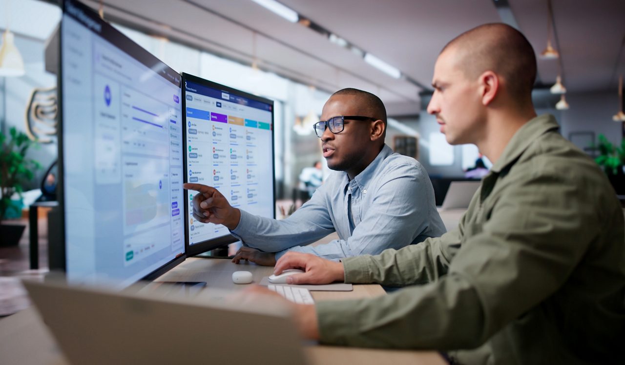 Two workers reviewing information on monitors 