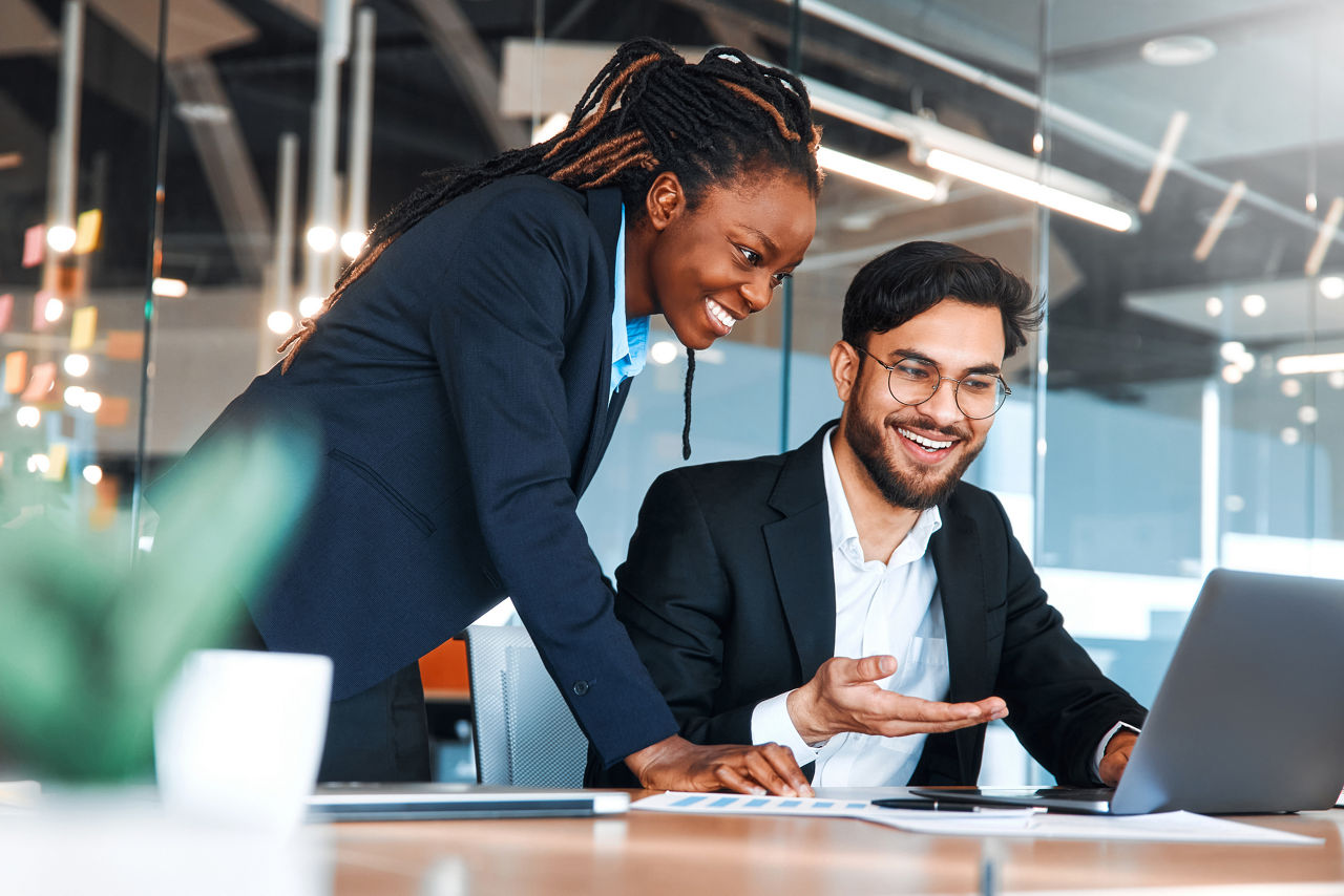 Successful young people working in a coworking space. African American Woman With Her Team Working With Laptop Discussing Strategy And Business Plan In Modern Office.