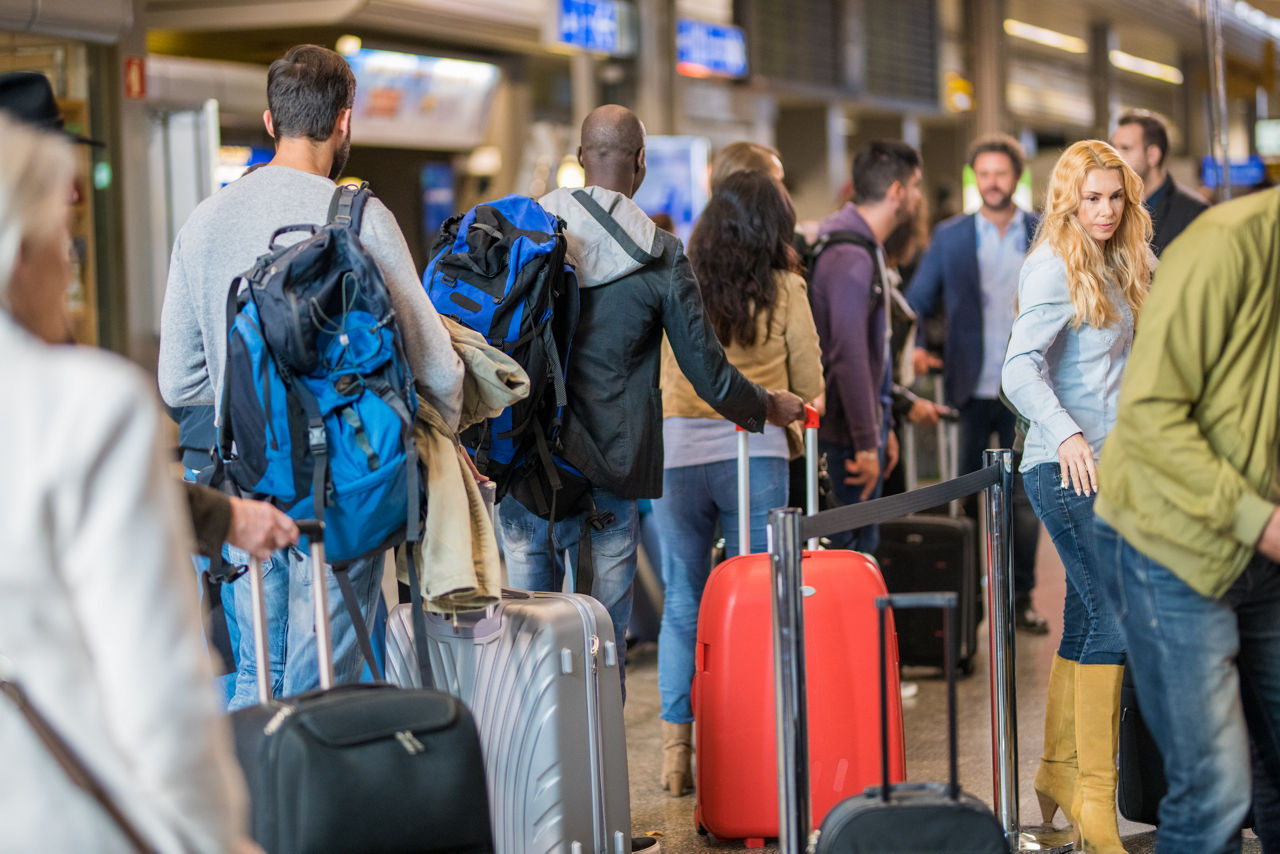 Business people standing with luggage in queue at airport arrival area.