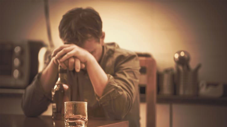A man sitting at a table with a glass of alcohol.