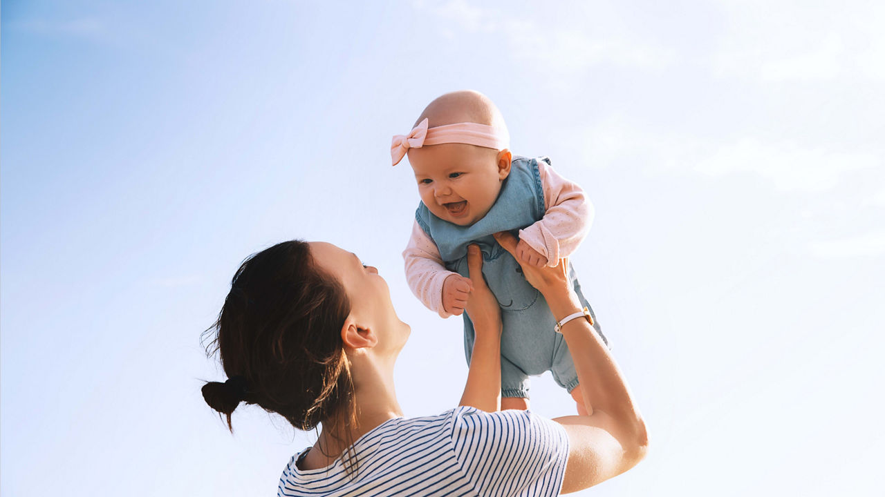 A woman is holding her baby up in the air.