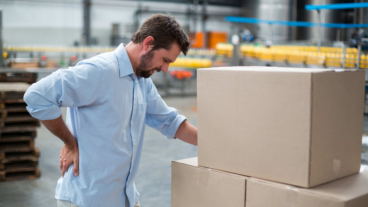 A man with a back pain in a warehouse.
