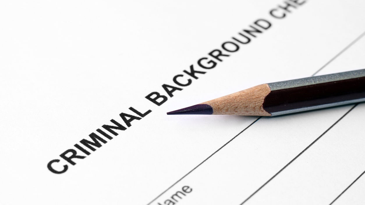A pencil sits on top of a criminal background check form.