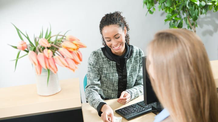 A woman is handing money to a customer in an office.