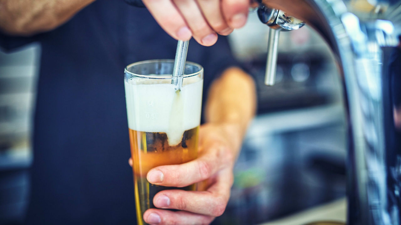 A bartender pouring a beer into a glass.