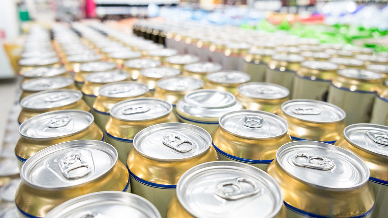 Many cans of beer are lined up in a store.