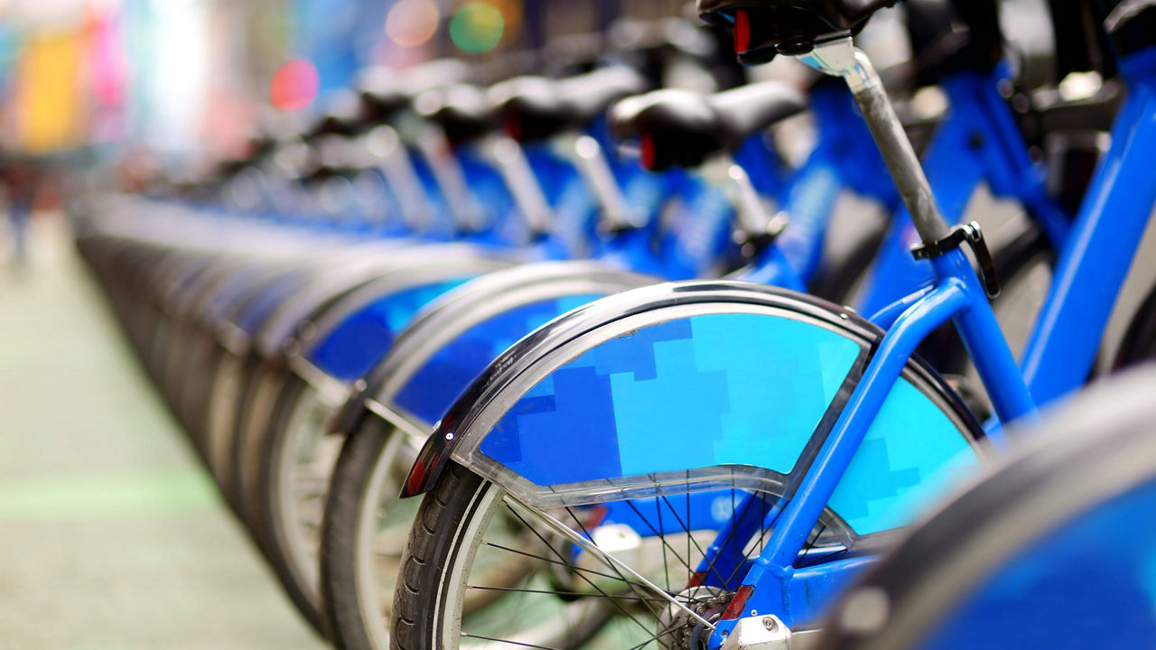 A row of blue bicycles parked on a street.