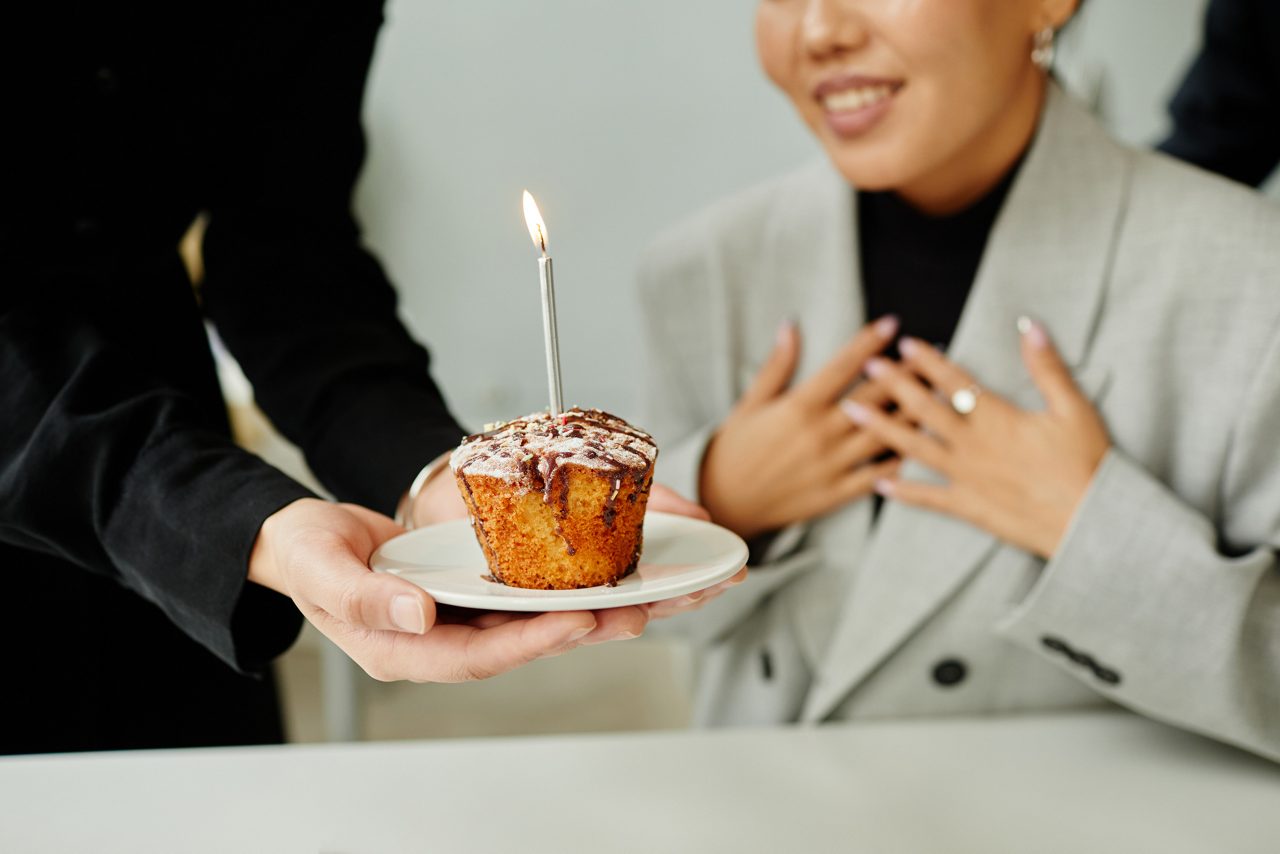 Co-worker presents a cupcake with candle to a colleague