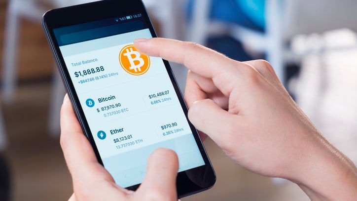 A person holding a smartphone with bitcoin on the screen.