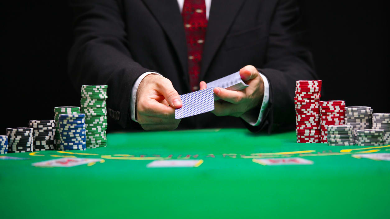 A man holding a card and chips at a casino table.